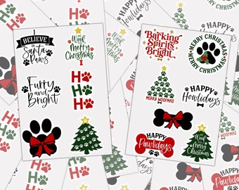 May include: A collection of Christmas stickers featuring dog-themed designs. The stickers feature paw prints, Christmas trees, and phrases like "Happy Howlidays" and "Woof Merry Christmas".