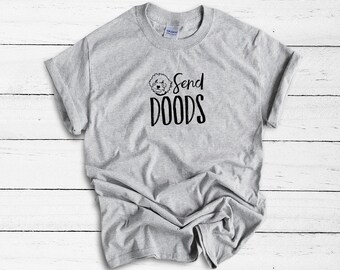 May include: A heather gray short-sleeve crew neck t-shirt featuring a black graphic of a curly-haired dog head above the text Send DOODS in a stylized font. The shirt has a standard fit with a visible brand label at the inner neckline.