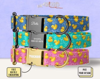 May include: Three pet collars featuring a yellow rubber duck and bubble pattern. The top collar is blue with a black buckle engraved with Bella. The middle is teal with a black buckle engraved with Shasta and 888-321-9876. The bottom is pink with a gold buckle engraved with Tucker.