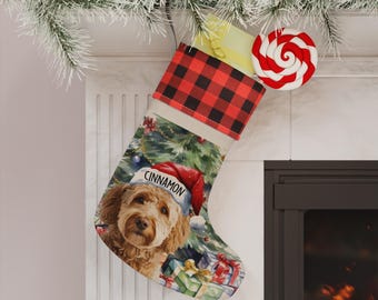May include: A Christmas stocking featuring a red and black buffalo plaid cuff and a printed illustration of a golden-brown dog wearing a red Santa hat with the name Cinnamon written on the brim, set against a background of gifts and a tree.