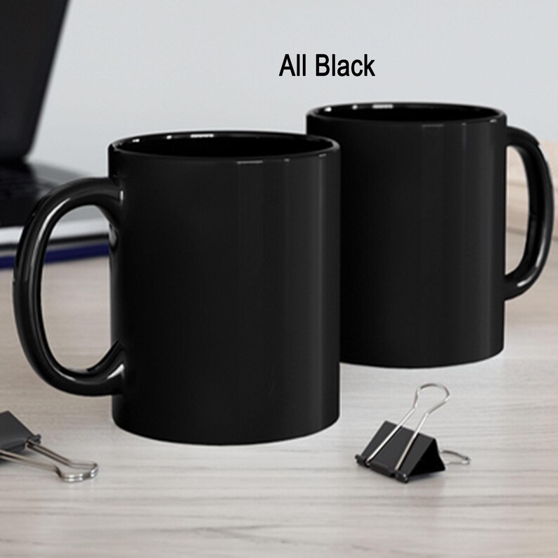 a couple of black coffee mugs sitting on top of a table