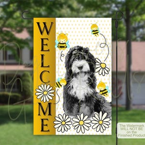 May include: A rectangular garden flag featuring a black and white dog illustration, three cartoon bees, and white daisies on a yellow and white polka dot background. The word WELCOME is printed vertically in black letters on a solid yellow side panel.