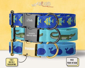 May include: Three personalized dog collars stacked on top of each other. The top collar is blue with yellow and blue fish. The middle collar is turquoise with green alligators. The bottom collar is blue with blue whales. Each collar has a metal buckle.