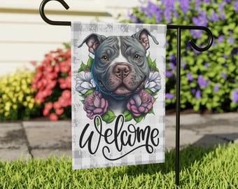 May include: A rectangular garden flag featuring a gray and white pit bull dog portrait surrounded by pink and white flowers. The background has a gray and white buffalo check pattern. The word Welcome is written in black cursive script below.