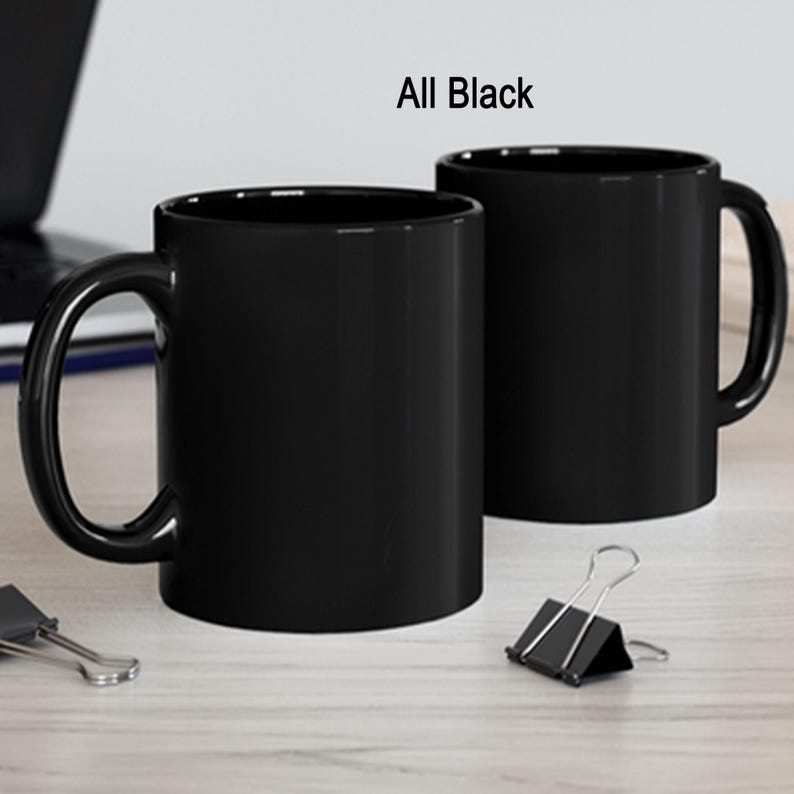 a couple of black coffee mugs sitting on top of a table