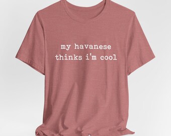 Puede incluir: Una camiseta de manga corta color rosa empolvado con el texto blanco "my havanese thinks i'm cool" impreso en el pecho. La esquina inferior derecha incluye el pequeño texto blanco "Customize with any breed name!"