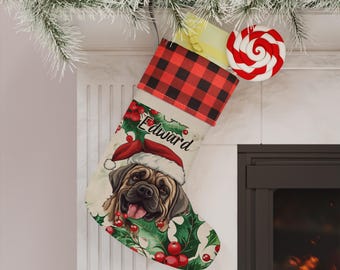 Könnte beinhalten: Ein Weihnachtsstrumpf mit rot-schwarz kariertem Umschlag, einem cremefarbenen Körper mit einer Grafik eines Hundes mit Weihnachtsmütze, grünen Stechpalmenblättern, roten Beeren und dem Namen Edward in schwarzer Schreibschrift.