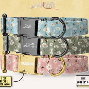 May include: Three dog collars with daisy and bee patterns. The top collar is light blue, the middle is olive green, and the bottom is pink. Each collar has a metal buckle with a name engraved. The collars have black or gold metal hardware.