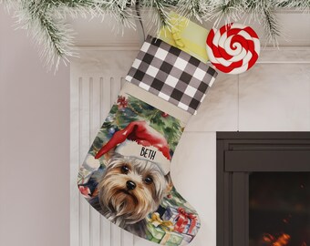 May include: A Christmas stocking featuring a black and white buffalo check cuff and a printed illustration of a Yorkshire Terrier wearing a red Santa hat with the name BETH printed on the brim, surrounded by colourful wrapped gift boxes.
