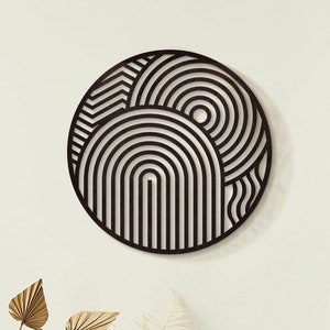 Op de afbeelding: Zwart-witte geometrische wandkunst in de vorm van een cirkel. Het ontwerp bevat overlappende concentrische cirkels en bogen.