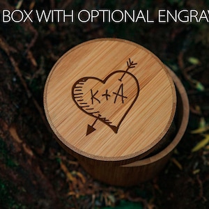 May include: A wooden gift box with a heart-shaped engraving. The heart has an arrow through it and the initials "K+A" inside. The box is made of light brown wood.