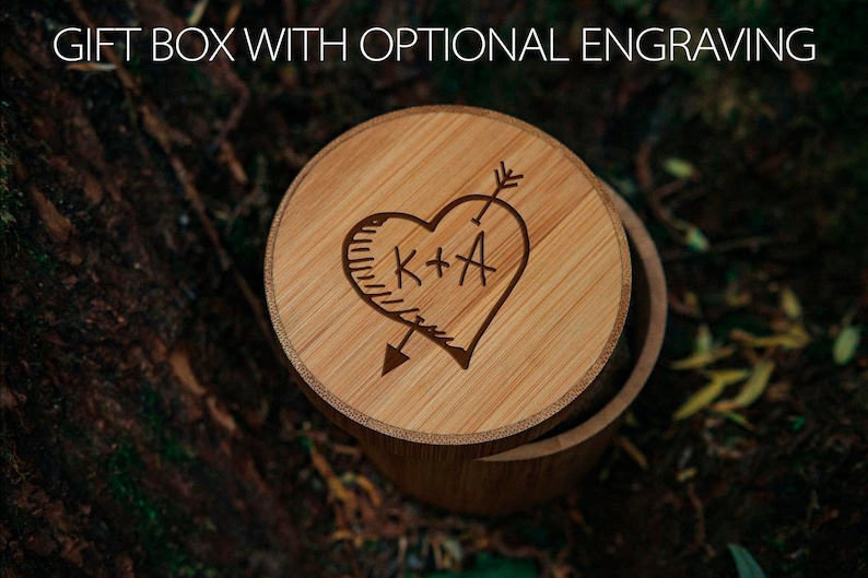 May include: A wooden gift box with a heart-shaped engraving. The heart has an arrow through it and the initials "K+A" inside. The box is made of light brown wood.