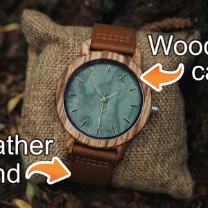 May include: A wooden wristwatch with a brown leather band. The watch face has a green background with gold-colored hands and markings. The text "Wooden case" is written above the watch and "Leather band" is written below the watch.