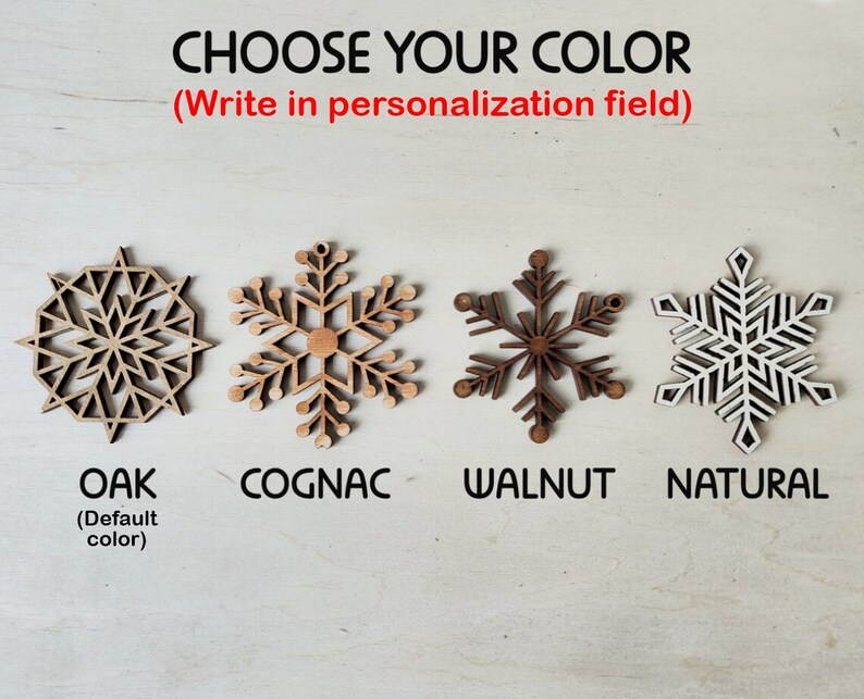 May include: Four wooden snowflake ornaments in different wood stains: oak, cognac, walnut, and natural. The text "CHOOSE YOUR COLOR (Write in personalization field)" is above the ornaments.