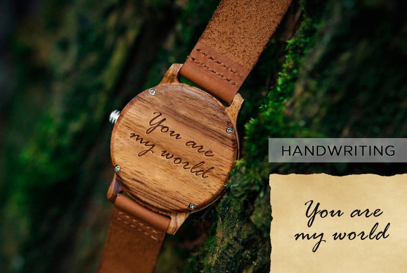 May include: A wooden wristwatch with a brown leather band. The watch face is engraved with the words "You are my world".