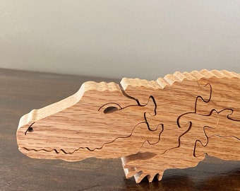 May include: A wooden alligator puzzle with intricate details. The puzzle is made of light brown wood and is assembled in a realistic pose.