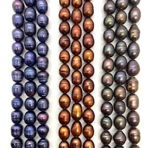 May include: Three vertical strands of beads arranged side by side. The left strand features dark purple and blue iridescent pearls. The center strand consists of copper and bronze-toned pearls. The right strand displays dark charcoal and black pearls.