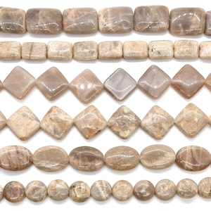 Puede incluir: Seis hileras horizontales de cuentas de piedra lunar pulida en varias formas. Las dos filas superiores presentan cuentas rectangulares, las dos centrales cuentas en forma de diamante y las dos inferiores cuentas ovaladas y circulares en tonos beige y gris.