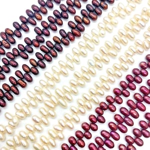 May include: Multiple strands of teardrop-shaped freshwater pearls arranged in parallel rows. The collection features alternating colour groups of deep dark purple, creamy white, and vibrant magenta pink pearls, each with a smooth, lustrous finish.