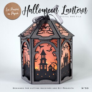 Puede incluir: Una linterna de Halloween hexagonal hecha de cartulina negra con purpurina y recortes intrincados de casas encantadas, &aacute;rboles desnudos y murci&eacute;lagos. Los paneles est&aacute;n forrados con papel naranja, iluminados desde dentro y rematados con un lazo negro.