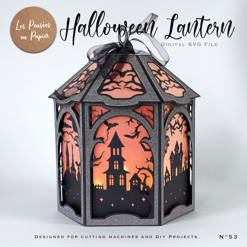 Puede incluir: Una linterna de Halloween hexagonal hecha de cartulina negra con purpurina y recortes intrincados de casas encantadas, &aacute;rboles desnudos y murci&eacute;lagos. Los paneles est&aacute;n forrados con papel naranja, iluminados desde dentro y rematados con un lazo negro.
