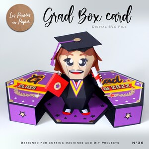 May include: A purple and gold graduation box card with a 3D pop-up of a cartoon graduate wearing a cap and gown. The card says "Grad Box Card" and "Class of 2022".
