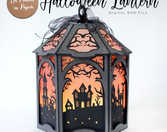 May include: A Halloween lantern with a black and silver frame, featuring cut-out silhouettes of haunted houses, bats, and trees against an orange glow. The text "Halloween Lantern" and "DIGITAL SVG FILE" are visible.