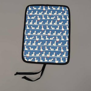 Può includere: Un cuscino per sedile in tessuto blu con un motivo di oche bianche. Il cuscino ha un bordo nero e una stringa di legatura nera.