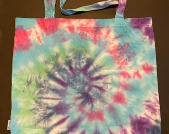 May include: A tie-dye tote bag with a blue, green, pink and purple swirl pattern.