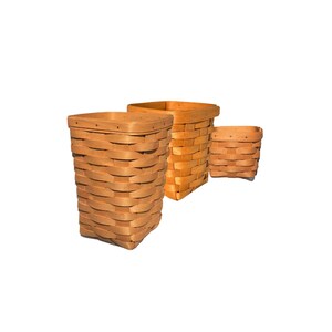 May include: Three woven baskets in different sizes. The baskets are made of light brown wood and have square lids. The largest basket is tall and rectangular, while the smallest is a small square. The baskets are arranged on a white background.