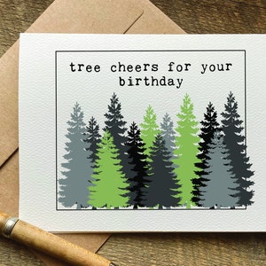 May include: A white card with the text "tree cheers for your birthday" and a graphic of a row of green, black, and gray trees.