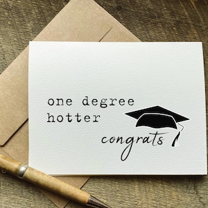 May include: A white card with black text that reads "one degree hotter congrats" and a black graduation cap illustration.