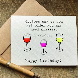 May include: A white card with a humorous birthday message that reads "doctors say as you get older you may need glasses. i concur. happy birthday!"  The message is illustrated with three wine glasses, one red, one pink, and one yellow.