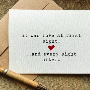 May include: A white card with the text "it was love at first sight... and every sight after." A red heart is printed between the two lines of text.