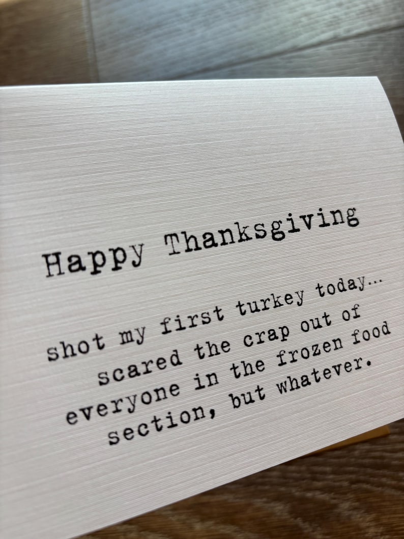 May include: A white greeting card with a textured surface featuring black typewriter-style text that reads: Happy Thanksgiving, shot my first turkey today... scared the crap out of everyone in the frozen food section, but whatever.