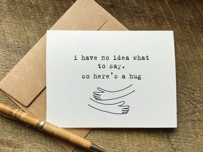 Puede incluir: Una tarjeta blanca con texto negro que dice "No tengo ni idea de qu&eacute; decir. As&iacute; que aqu&iacute; tienes un abrazo" y un simple dibujo de l&iacute;nea de dos brazos abraz&aacute;ndose.