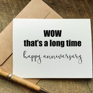 May include: A white card with black text that reads "WOW that's a long time happy anniversary".