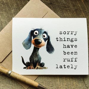May include: A greeting card with a cartoon illustration of a black and blue dachshund dog. The text on the card reads "sorry things have been ruff lately".