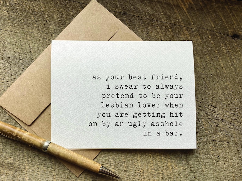 May include: A white greeting card with black typewriter-style text that reads: as your best friend, i swear to always pretend to be your lesbian lover when you are getting hit on by an ugly asshole in a bar. The card is paired with a brown envelope.