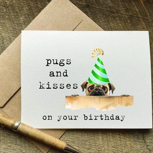 May include: A white card with the text "pugs and kisses on your birthday" and a pug wearing a green and white party hat peeking over the top of the card.