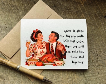 Puede incluir: Una tarjeta de felicitación blanca con una ilustración de estilo vintage de una pareja con un pavo asado, un cuenco de relleno y una calabaza. El texto dice: going to glaze the turkey with LSD this year. then we will see who has their shit together.