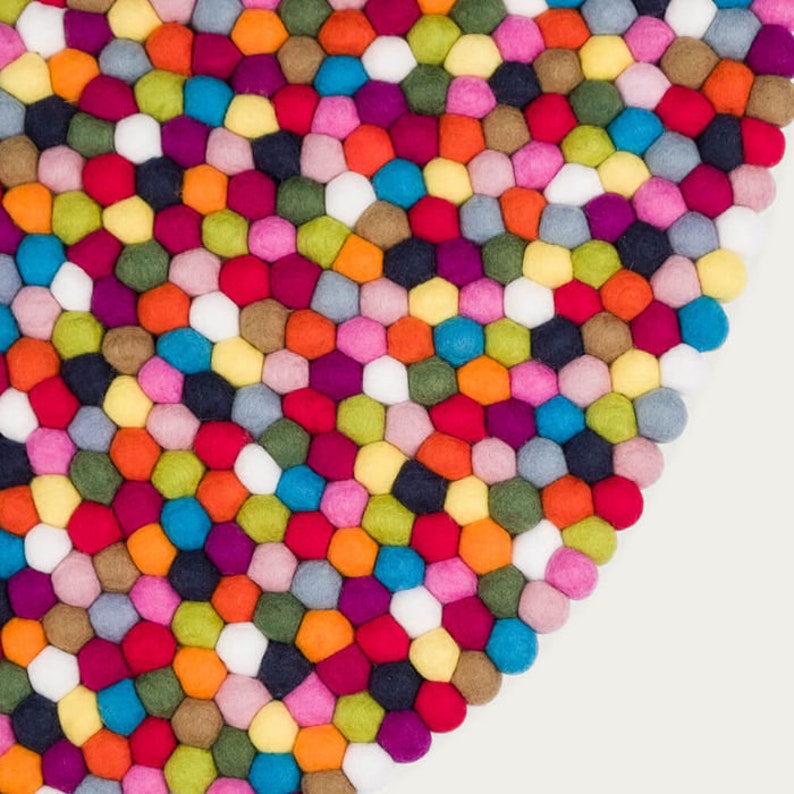 May include: A colorful round rug made of felt balls in various shades of red, orange, yellow, green, blue, purple, pink, brown, white, and gray. The balls are arranged in a circular pattern, creating a unique and eye-catching design.