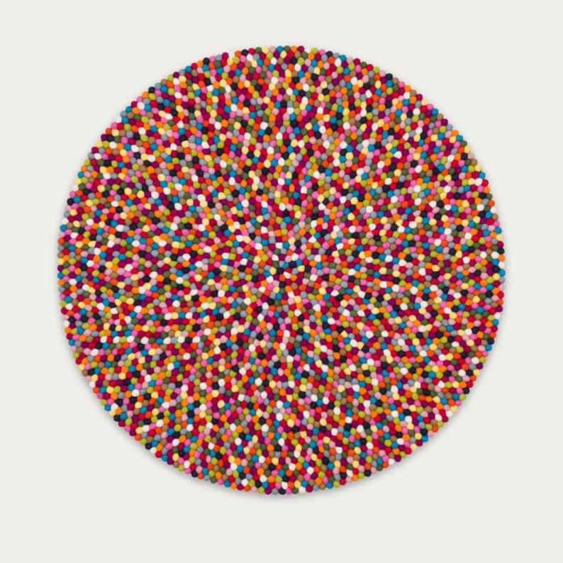 May include: A round, colorful rug made of felt balls. The rug is a mix of bright colors, including red, orange, yellow, green, blue, purple, and pink.