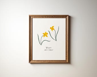 May include: A framed print of a botanical illustration featuring two yellow daffodils with green stems and leaves. The print is titled "Daffodil" with the artist's name "Wilbur Edgar" written below.