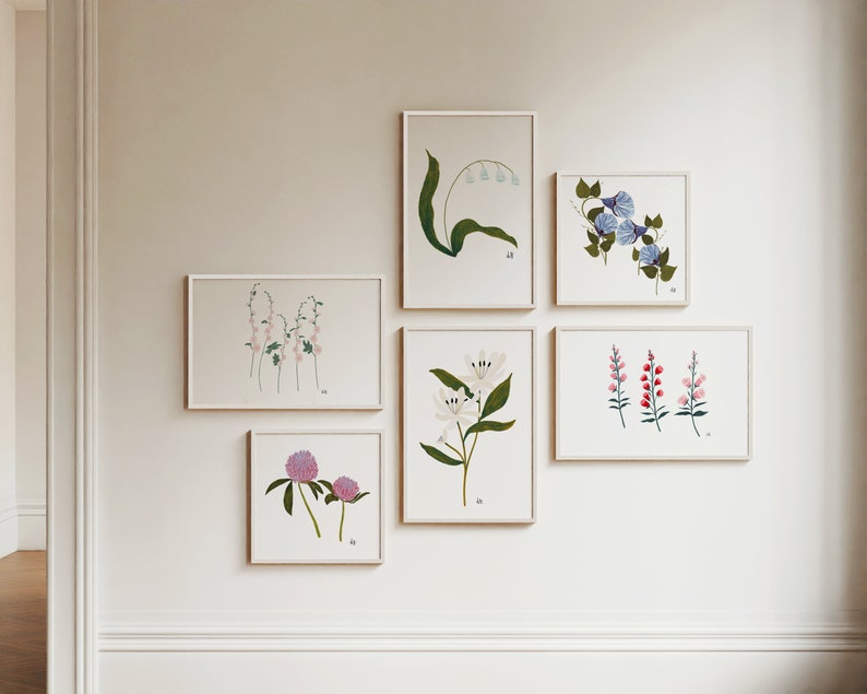 May include: A collection of six framed botanical prints featuring various flowers, including lilies, clover, and morning glories. The prints are arranged in a grid pattern on a white wall.