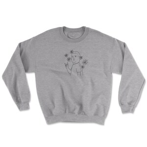 May include: A gray sweatshirt with a black line drawing of a cartoon character with a surprised expression. The character is wearing a t-shirt and has a flower crown. The character is making a rock and roll hand gesture.