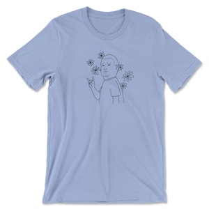 May include: A light blue t-shirt with a black line drawing of a cartoon character with a surprised expression, giving a rock and roll hand gesture. The character is surrounded by black line drawings of daisies.