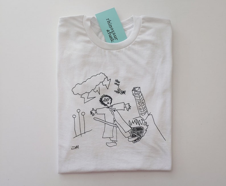 May include: White t-shirt featuring a black and white illustration of a person wearing glasses with a cloud and lightning bolts above them. The text "rhino & funk" is on a blue tag.