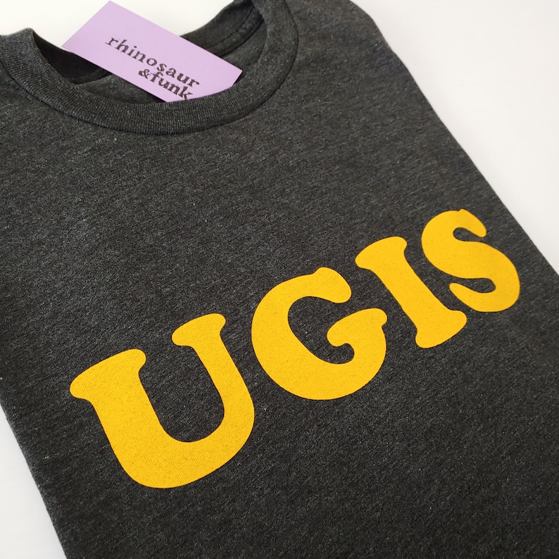 May include: A dark grey t-shirt with the word "UGIS" printed in yellow.