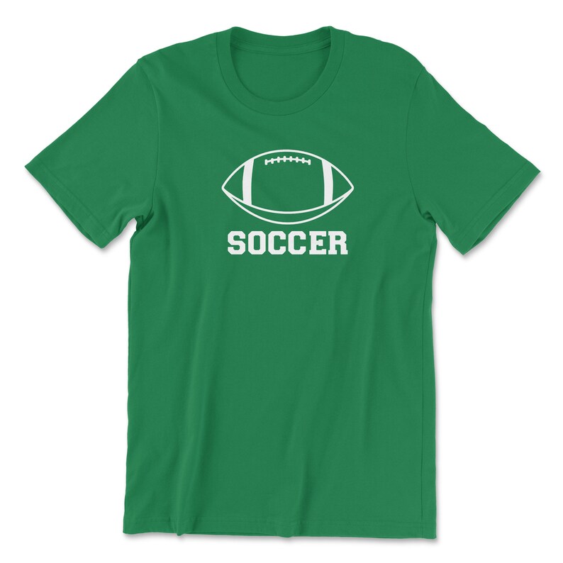 May include: A green t-shirt featuring a white graphic of a football with the word "SOCCER" printed below it in a bold, sans-serif font. The shirt is made of a soft material and has short sleeves and a crew neck.